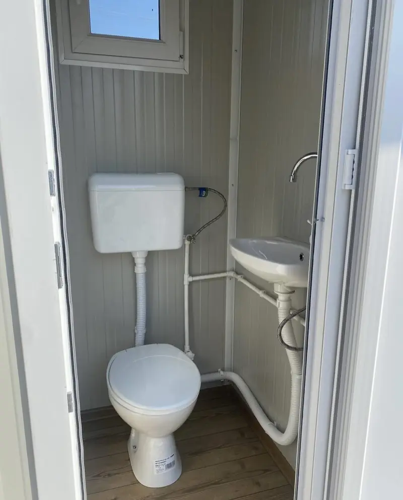 Flush toilet and foot-pump sink inside a deluxe unit.