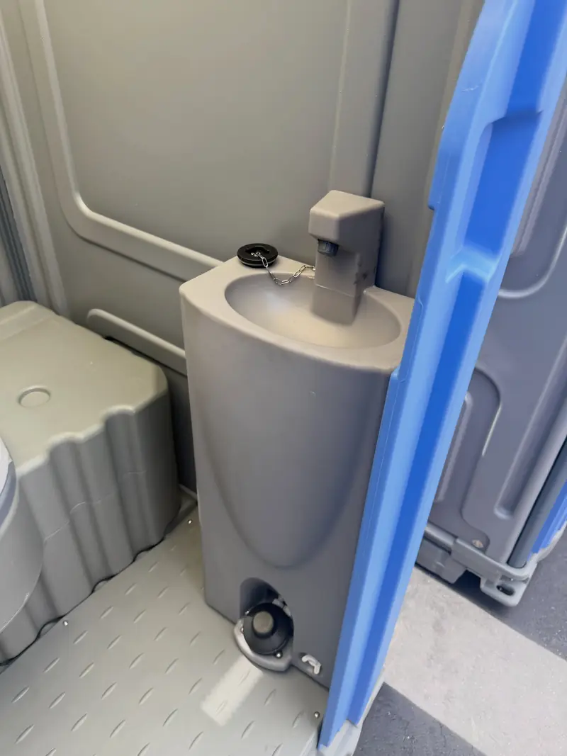 A built-in foot-pump sink keeps hand washing inside the stall.