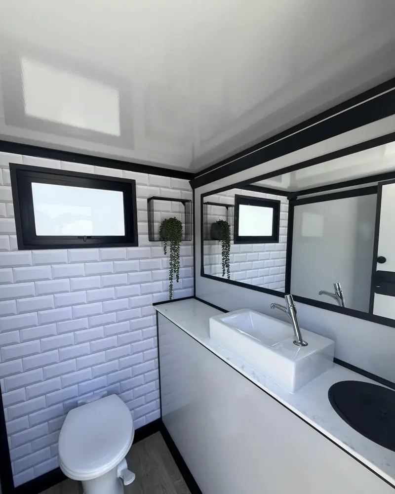 Vanity with vessel sink and mirror inside a restroom trailer.