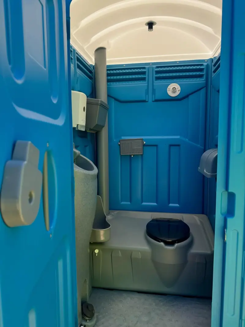Inside a blue standard porta potty showing the toilet seat and urinal