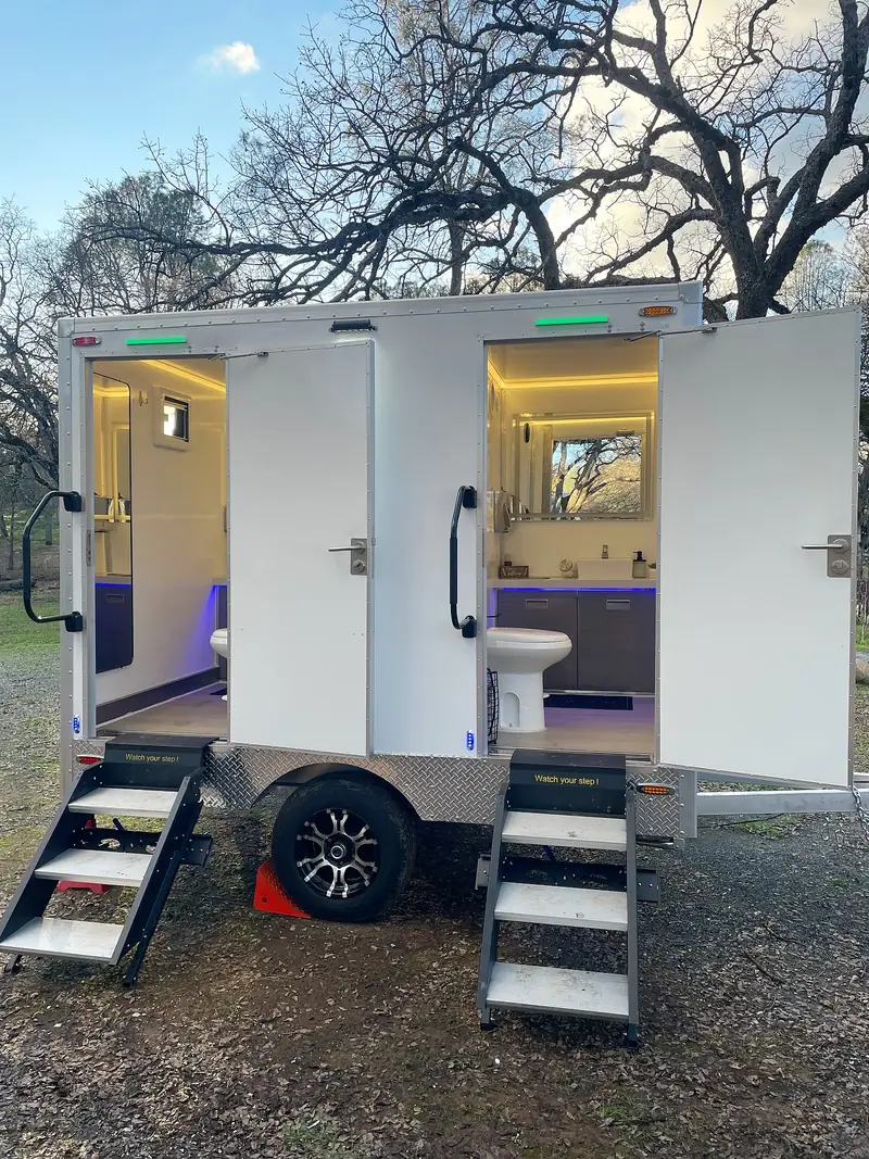 Two-stall restroom trailer with doors open and lights on